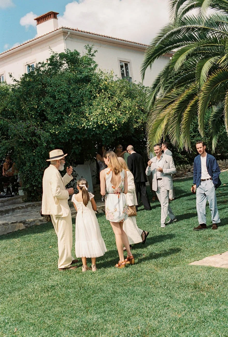 elegantly dressed guests enjoy themselves in a garden wedding in Lisbon, photographed on Portra 400 film