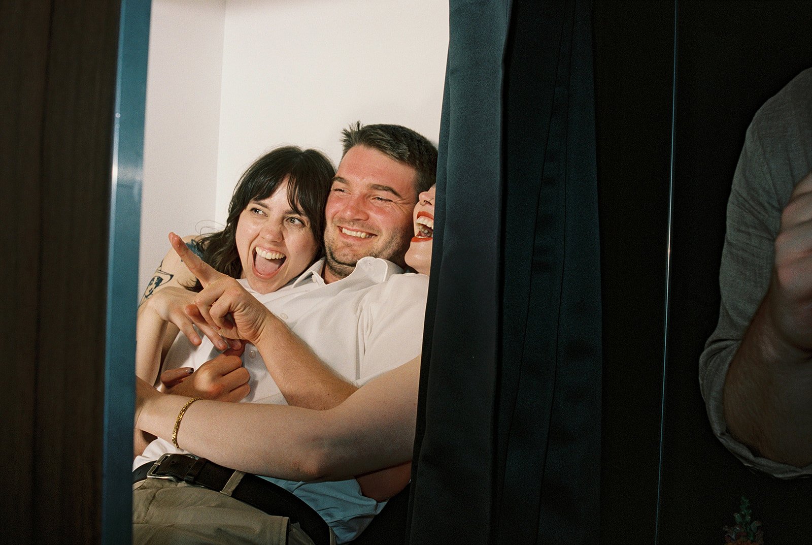 Three guest laughing and posing closely together in a photo booth by Montpellier wedding photographer