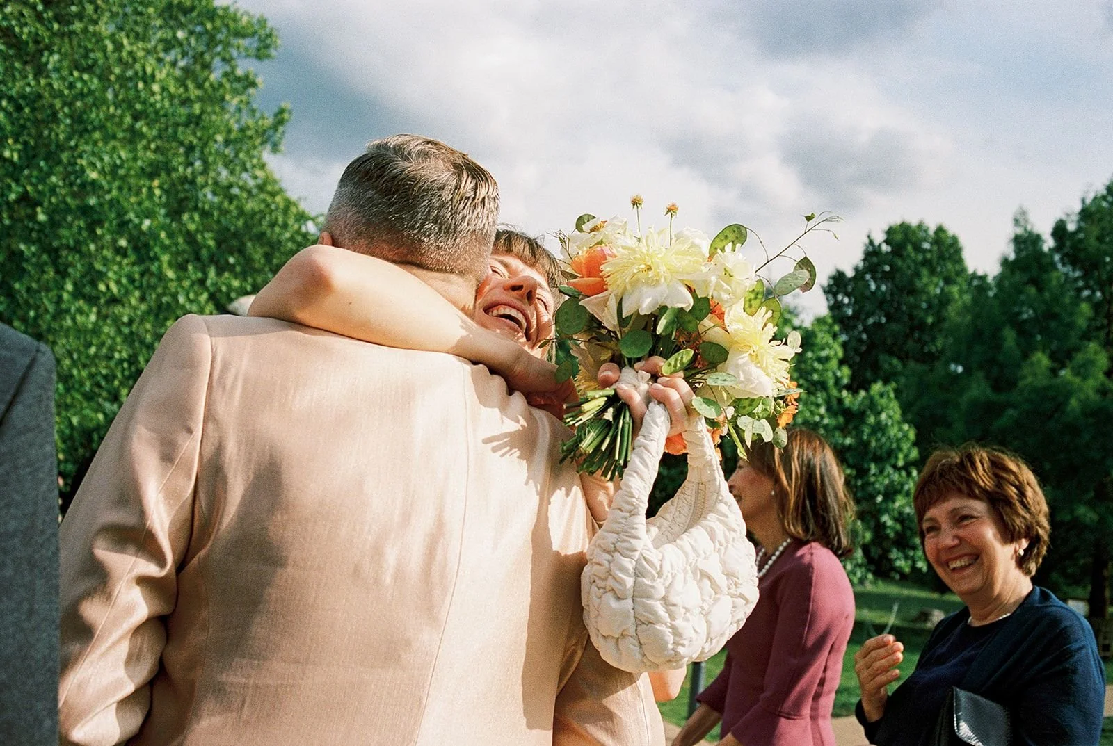Bride embracing guest while holding bouquet on her Dulwich Picture gallery wedding.