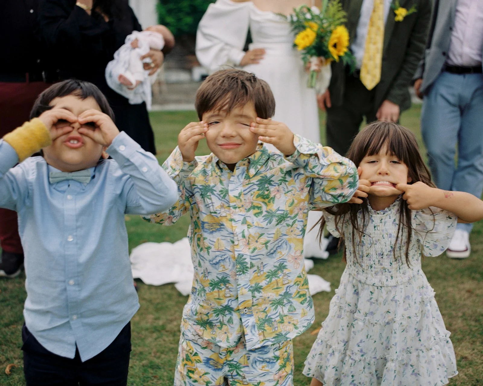 Kids being funny in colourful outfits at wedding formal photos.