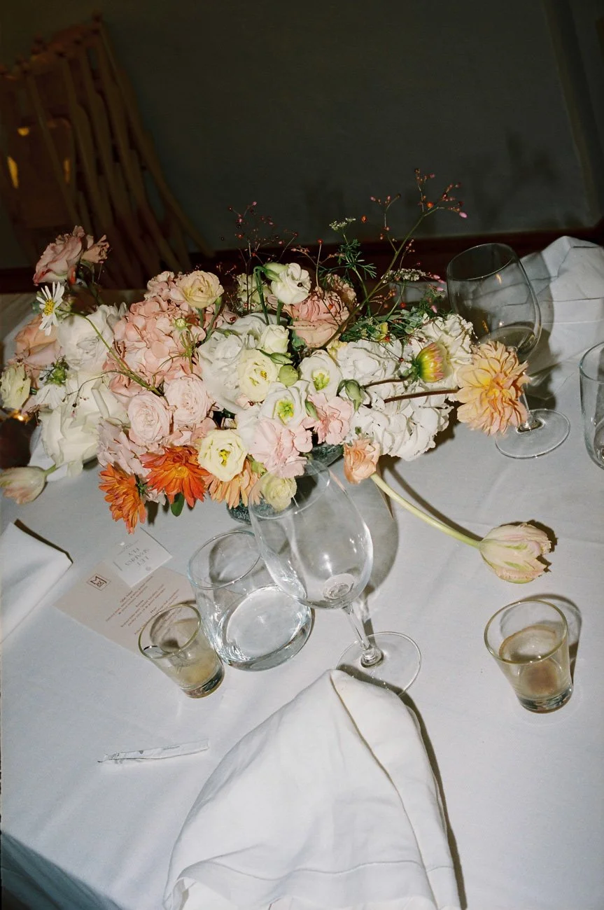 A dutch-painter inspired flower centerpiece with pastel flowers on a white tablecloth.