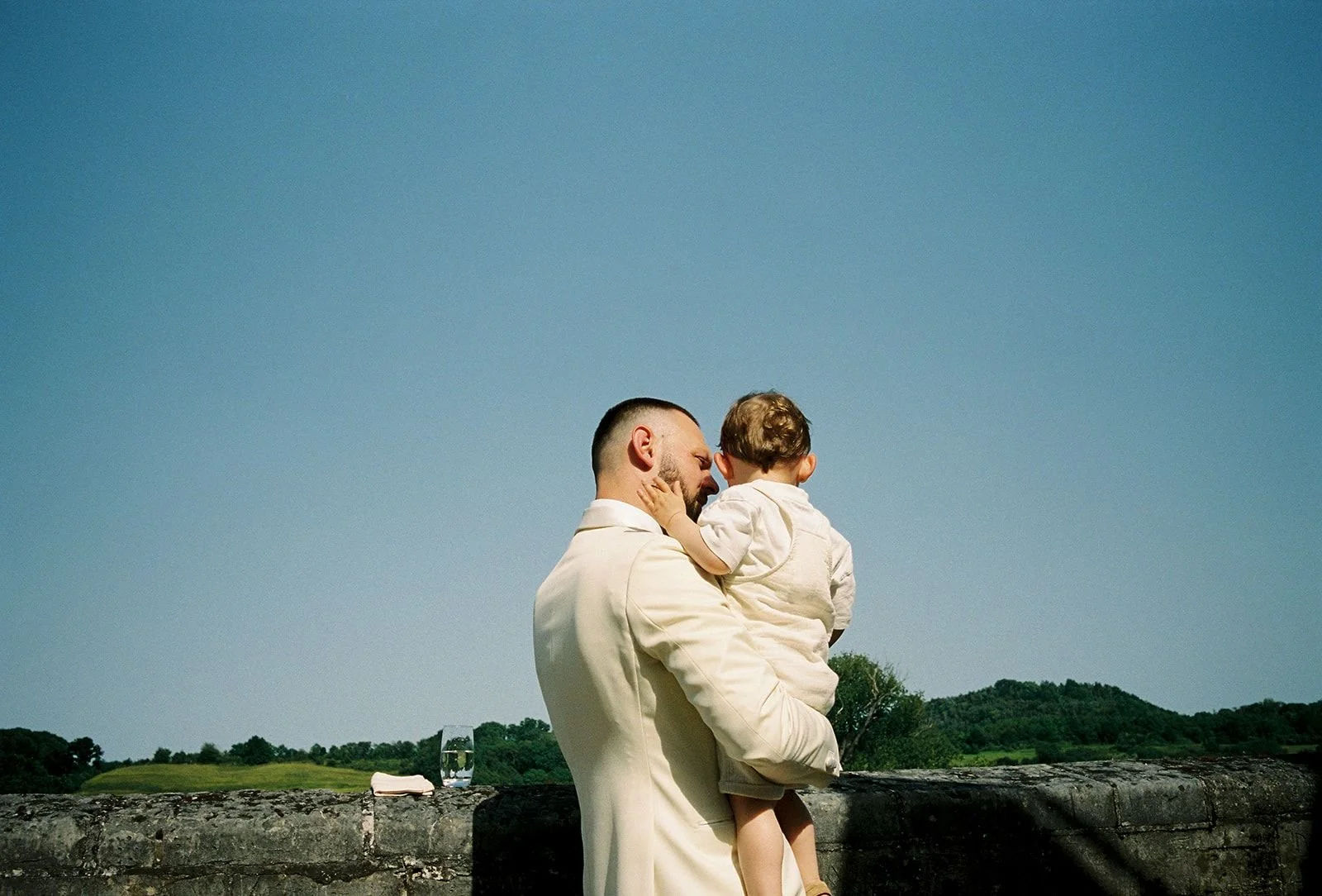 Groom holds son looking over Chateau's Neercanne view