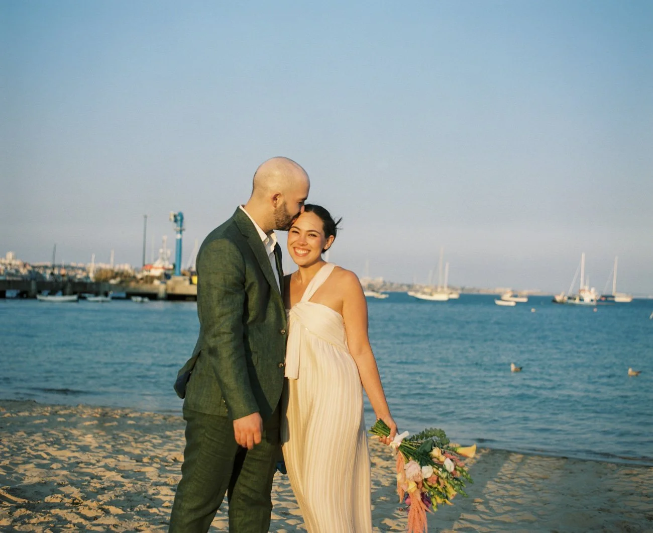 Bride and groom embracing by the ocean at sunset, photographer on color film by Algarve wedding photographer