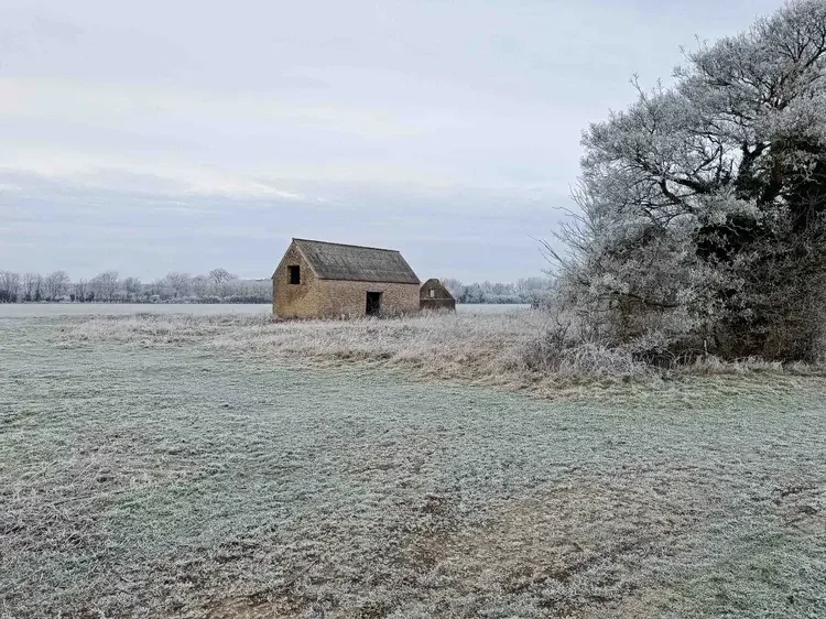 Historic stone agricultural barn in a frost-covered rural landscape, highlighting traditional heritage architecture and conservation potential.