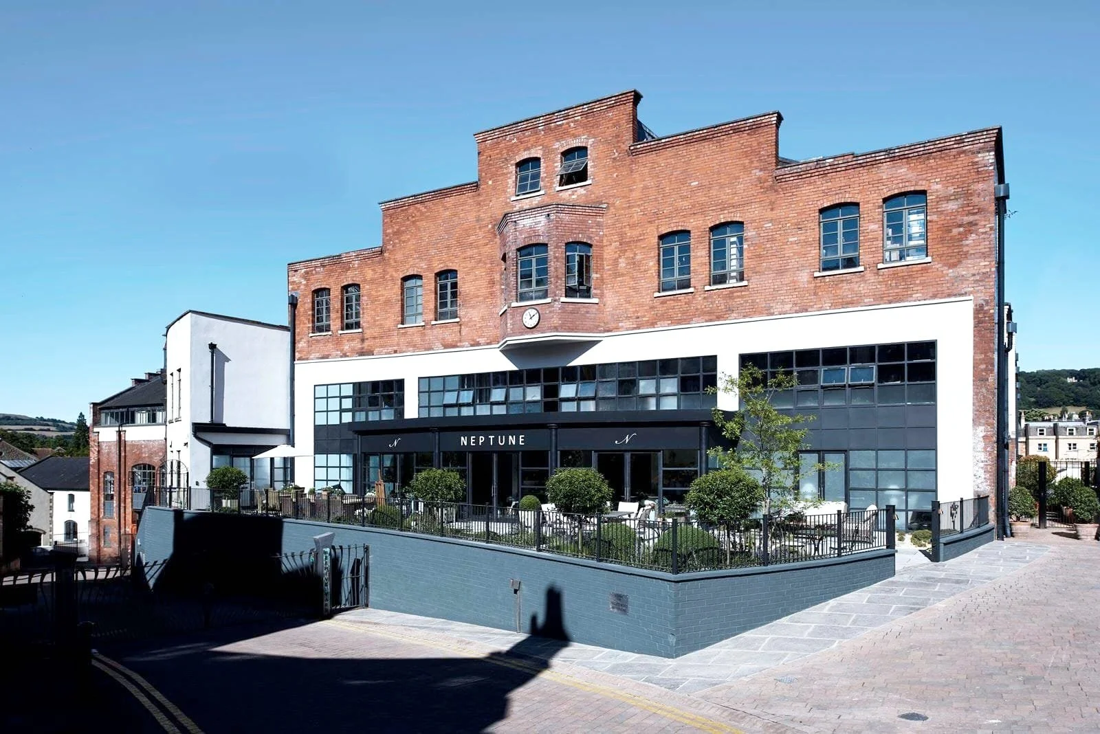 Large-scale historic brick industrial building converted into a modern mixed-use development with commercial frontage and outdoor terrace space.