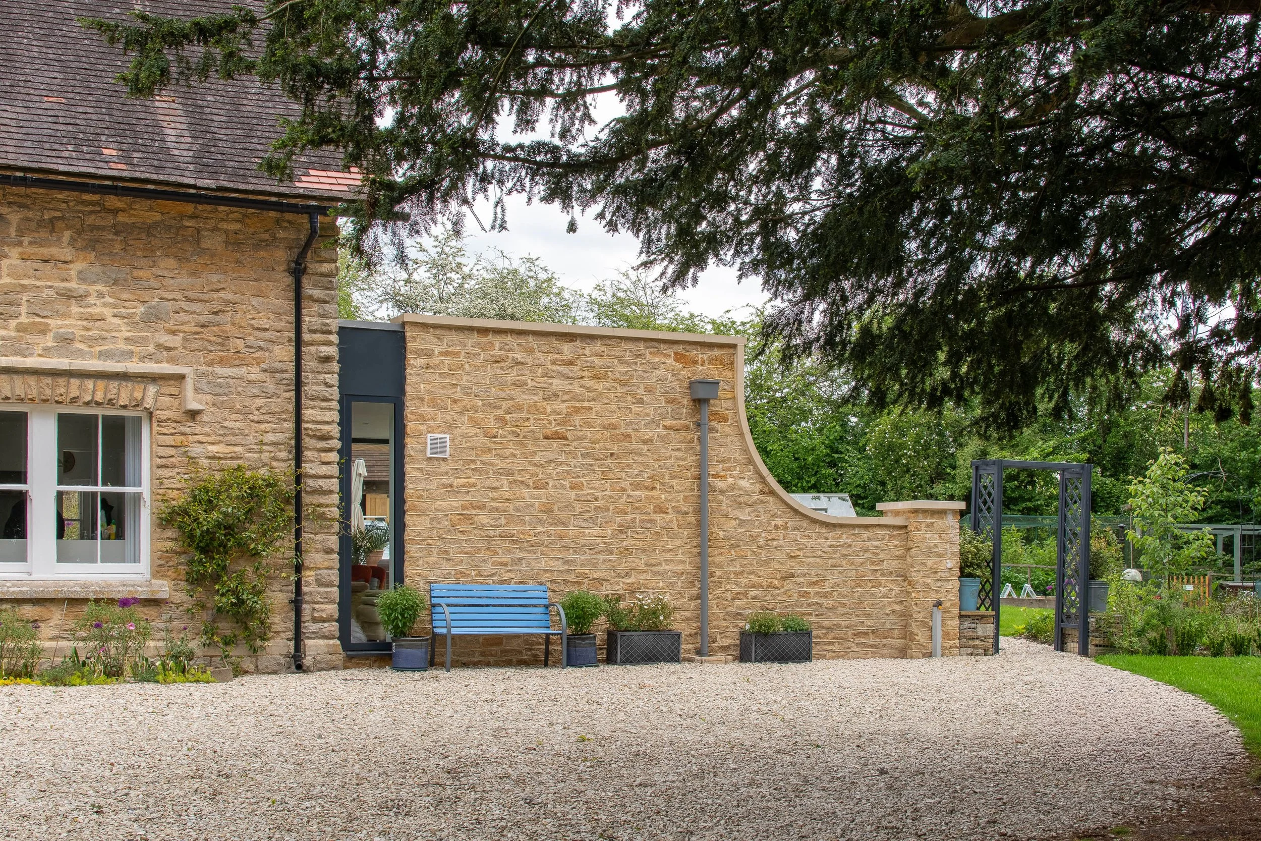 A tailored architectural slot window framing natural daylight along the gravel driveway.