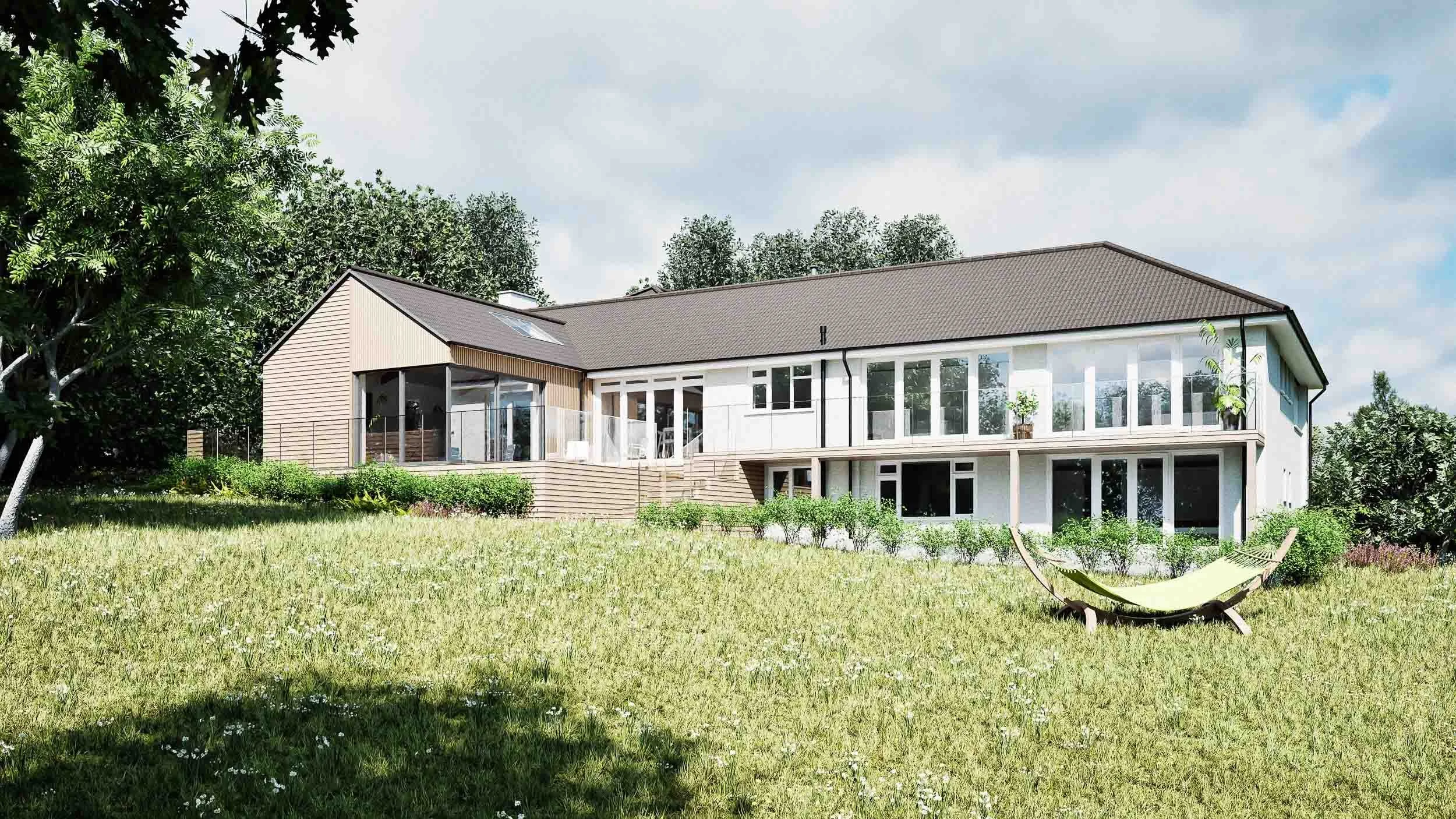 Rear view of a detached house with a new modern timber-clad extension, extensive wood decking, and a first-floor balcony with a glass balustrade.