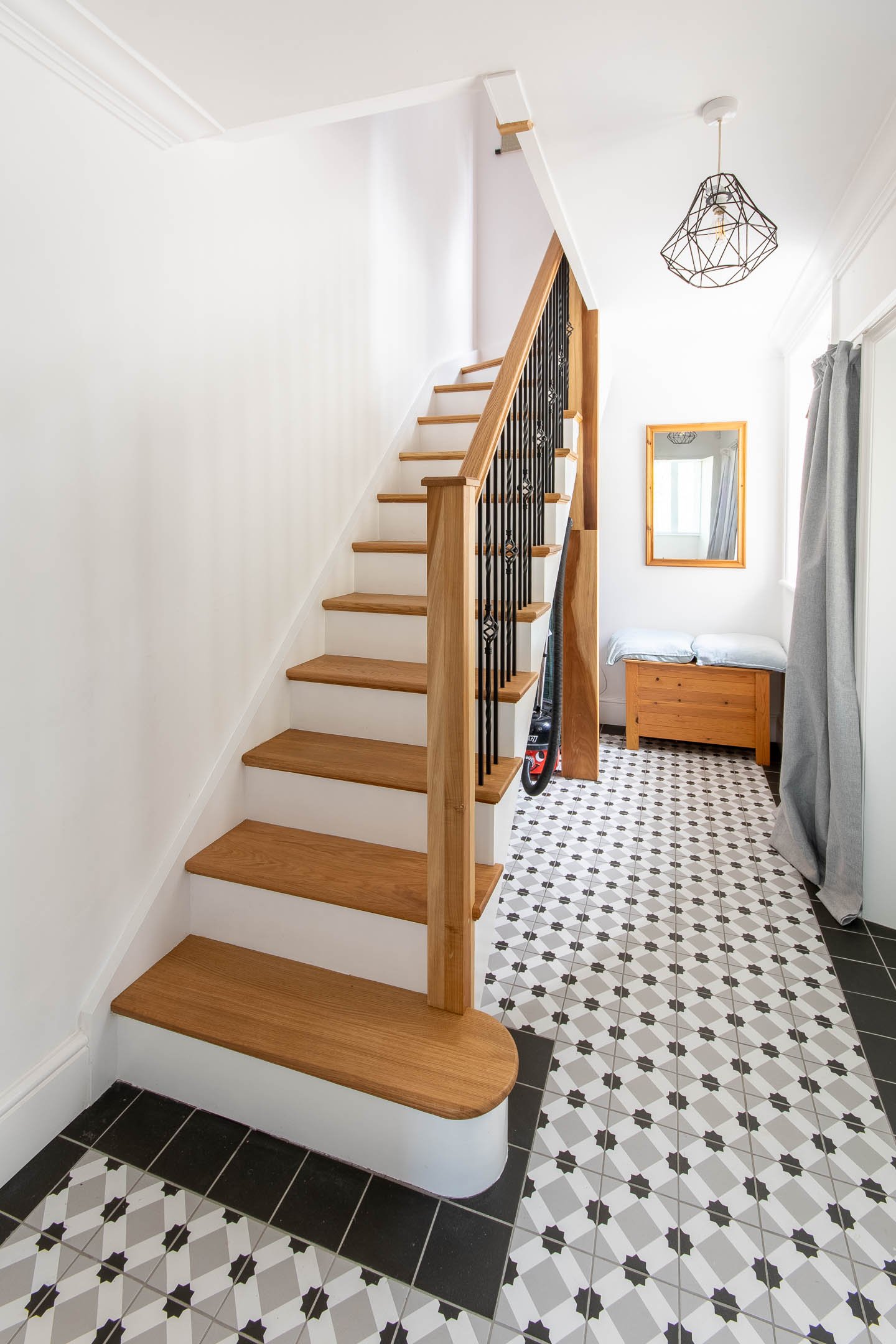 Bright entrance hallway featuring traditional geometric floor tiling and a refurbished oak staircase.