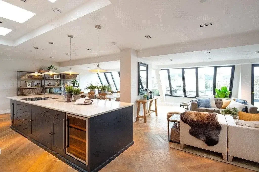 Open-plan contemporary kitchen and living space inside a historic industrial tram shed conversion in Bath, featuring large windows and a central kitchen island.