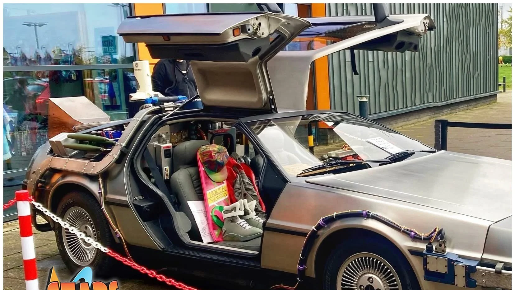 A DeLorean car from the movie 'Back to the Future' with various props and decorations inside and outside, including a skateboard, cap, and shoes.