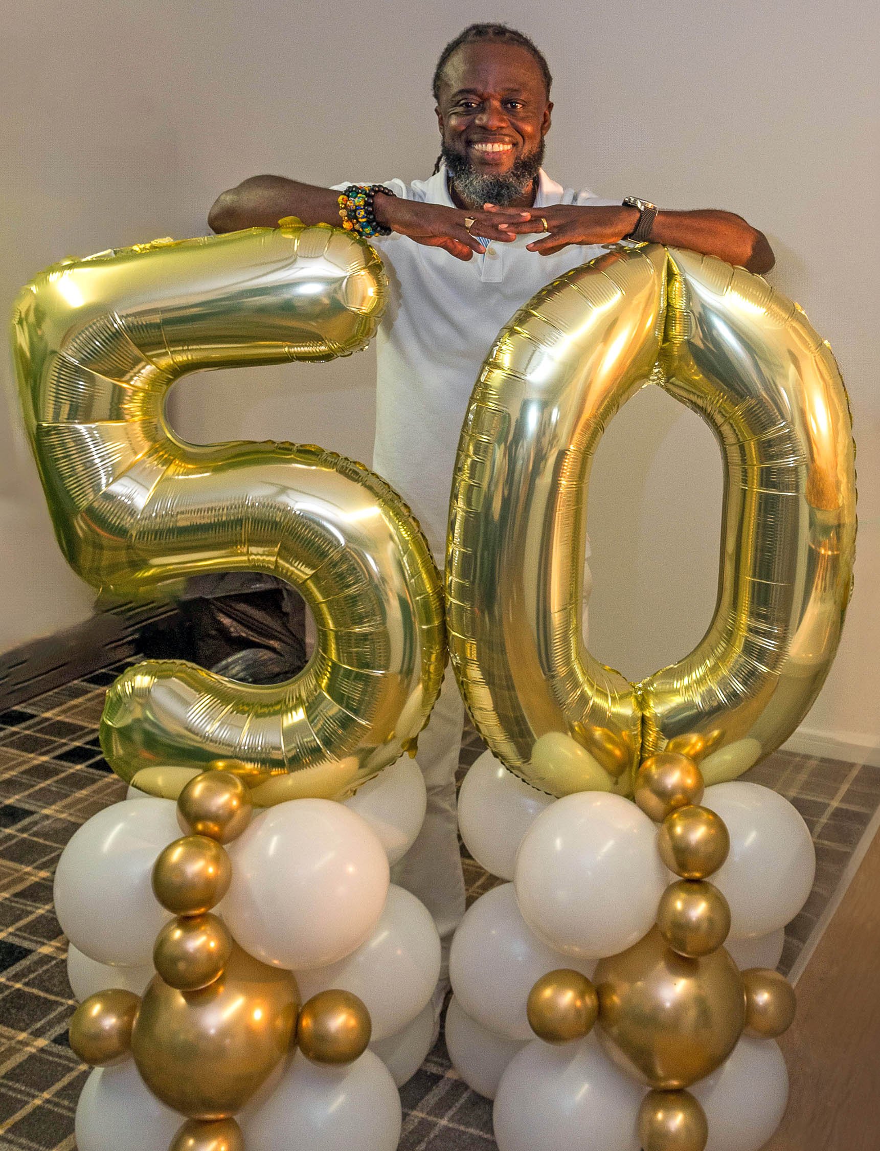 Birthday boy poses behind large 50 balloons