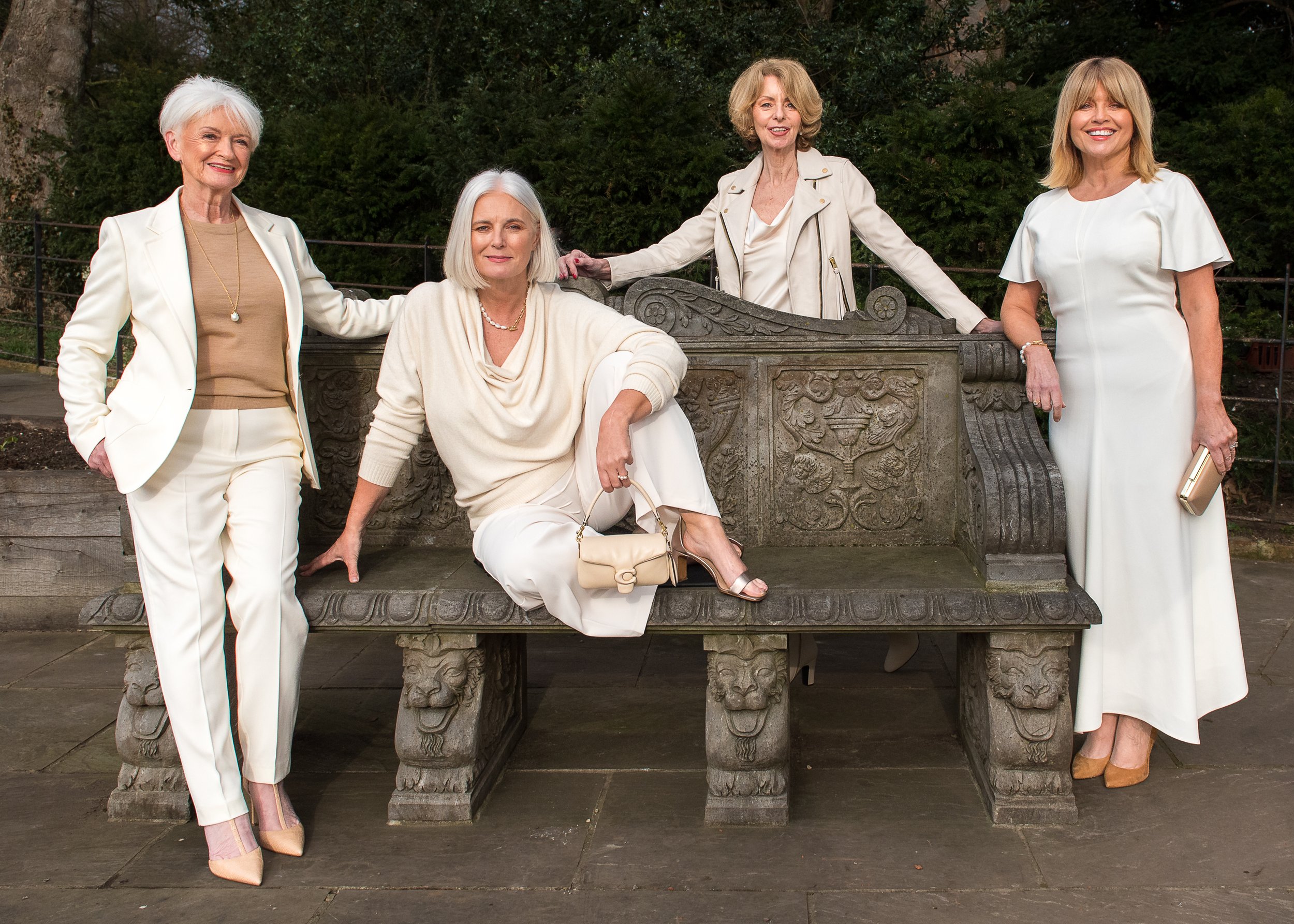 A sophisticated and stylish outdoor photoshoot featuring three elegant women in coordinated neutral outfits. A perfect example of timeless fashion and friendship captured in a confident and empowering setting.