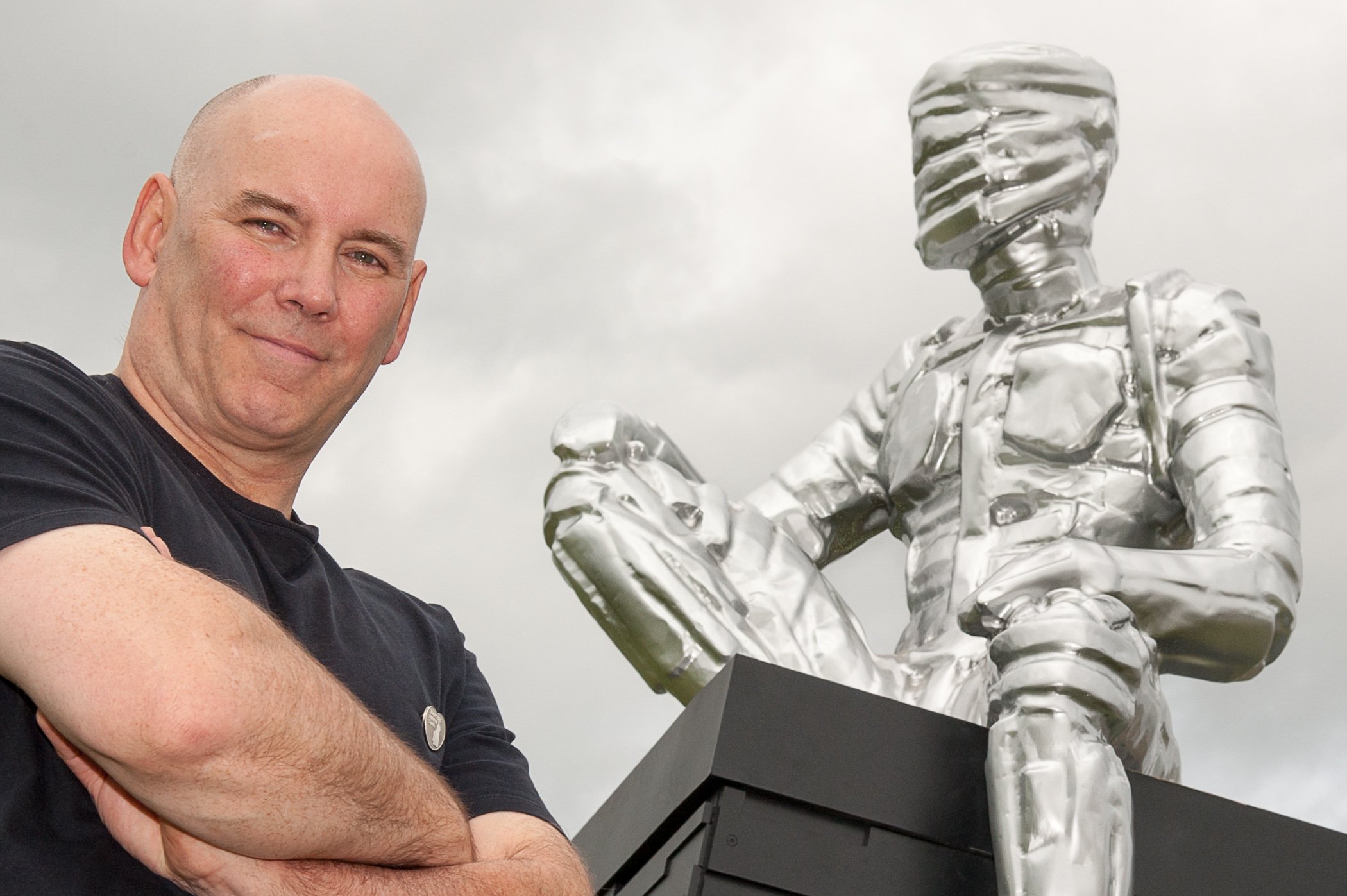 Artist with his sculpture of a man high on a plinth