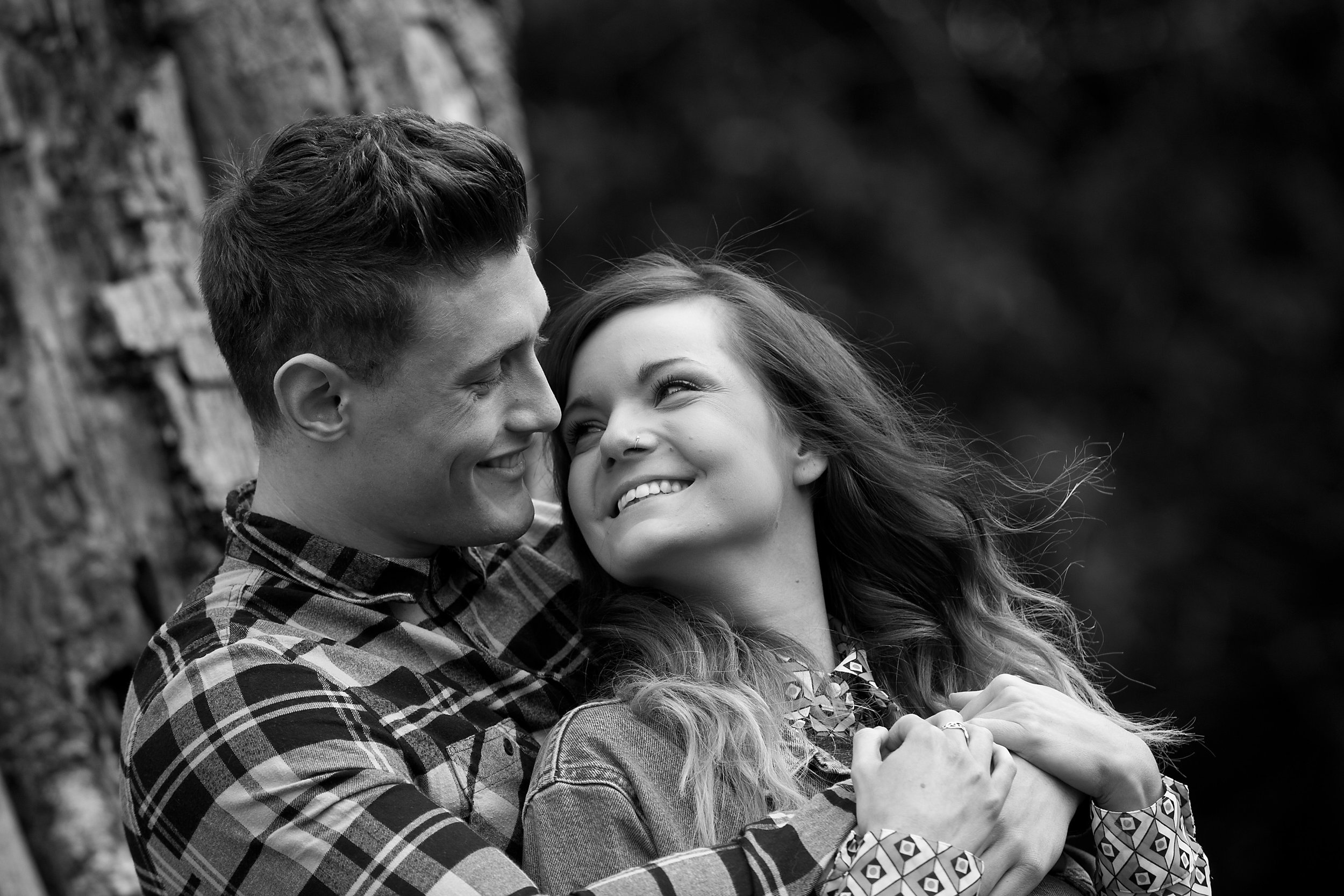 An intimate black-and-white portrait capturing a joyful couple embracing outdoors, radiating love. Perfect for engagement, wedding and lifestyle photography