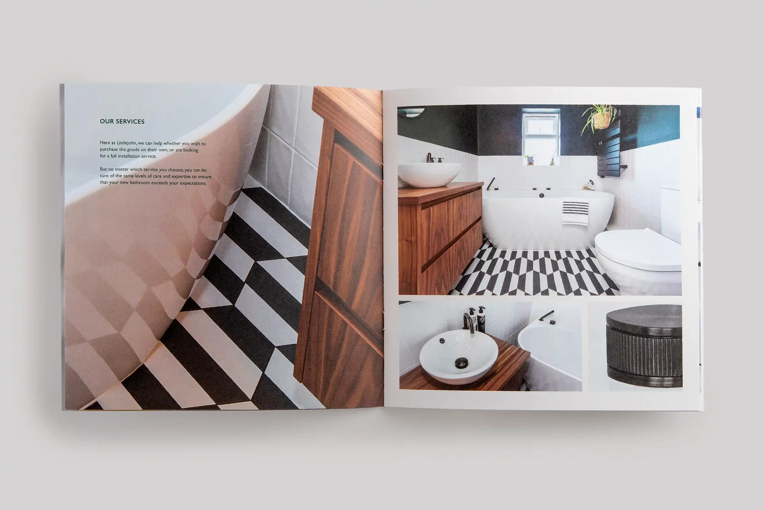 Open magazine showing bathroom images and text about bathroom services, including a black-and-white checkered floor, a bathtub, a wooden vanity with a vessel sink, a toilet, and a round black side table.