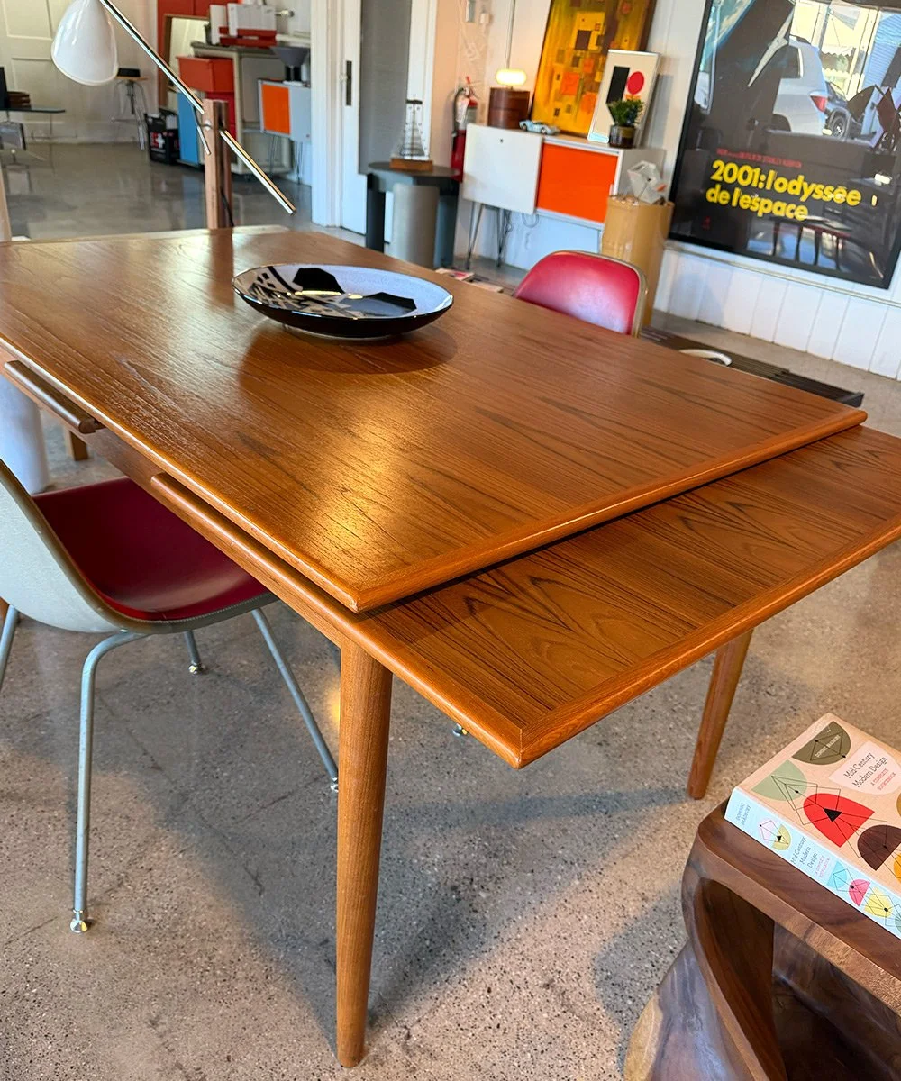 Vintage Danish modern teak dining table with extension leaves, featuring warm wood grain and clean mid-century lines. A timeless and functional MCM design at Design Culture GR.