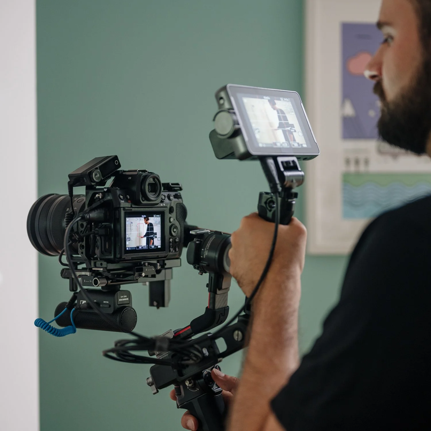 Ein Mann filmt mit einer professionellen Kamera in einem Raum mit grüner Wand. Die Kamera ist auf einem Gimbal stabilisiert.