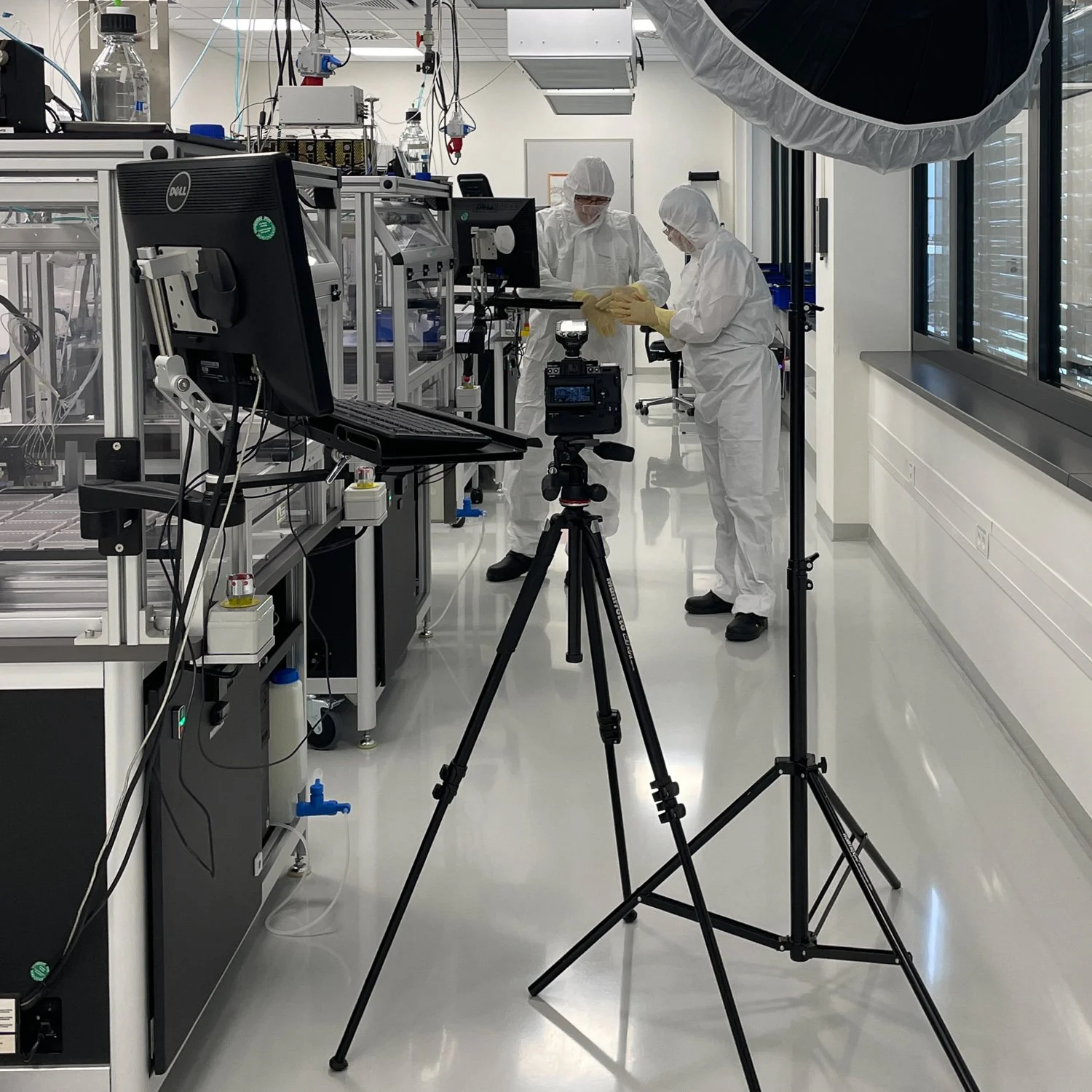 Wissenschaftler in Schutzkleidung arbeitet in einer Laborumgebung mit Kameras und Beleuchtungsausrüstung.