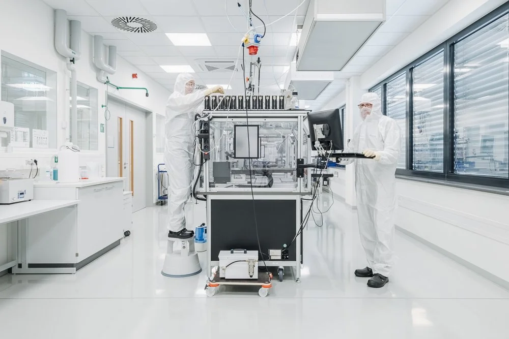 Wissenschaftler in einem modernen Labor mit Schutzkleidung arbeiten an einem komplexen Forschungsgerät.