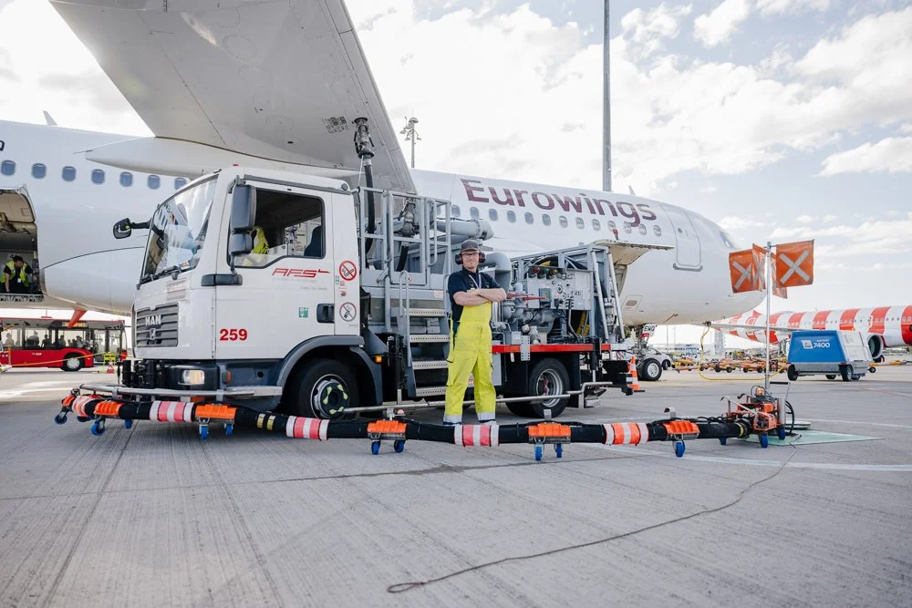 Arbeiter in Sicherheitsweste mit Wasserwagen an einem Flugzeug am Flughafen.