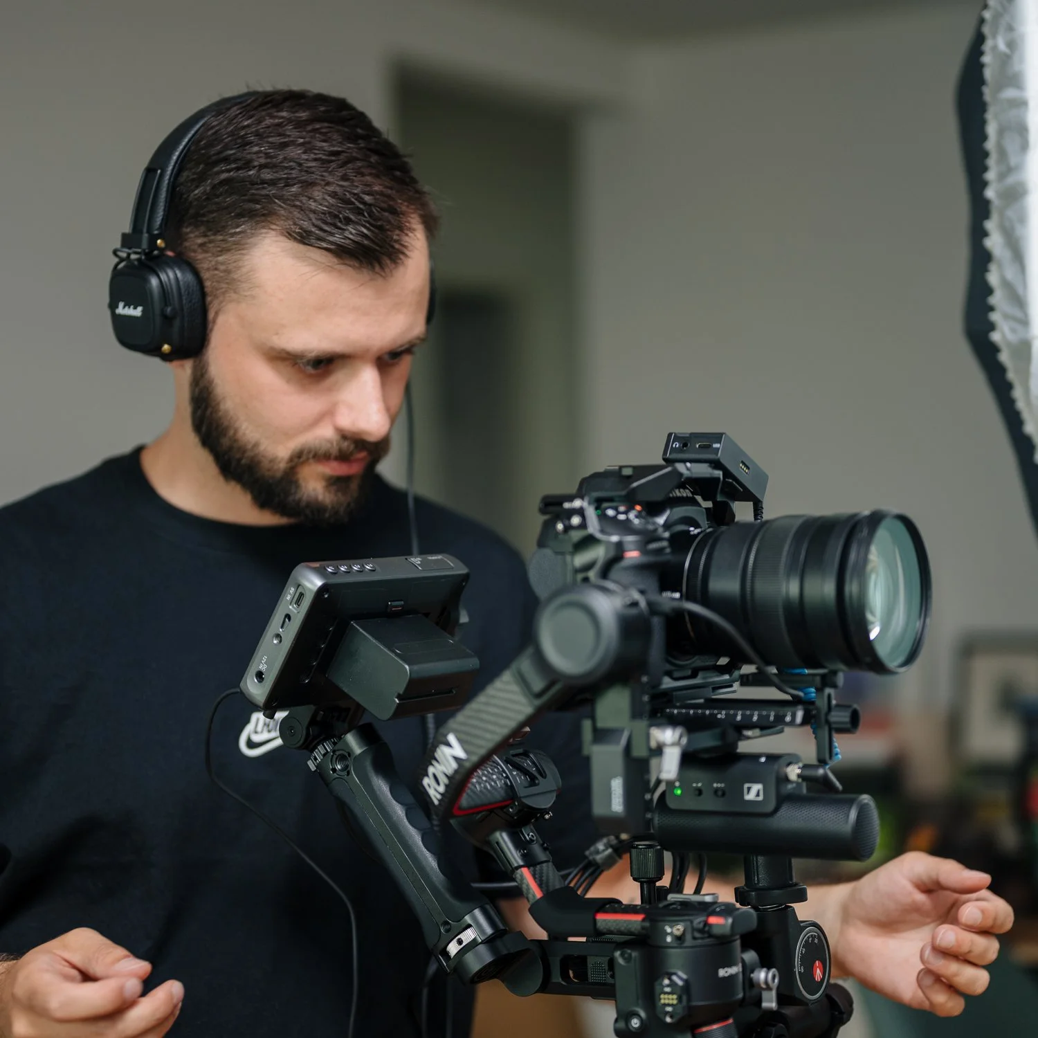 Ein Mann mit Kopfhörern bedient eine professionelle Kamerasysteme bei der Aufnahme eines Videos oder Fotos in einem Innenraum.