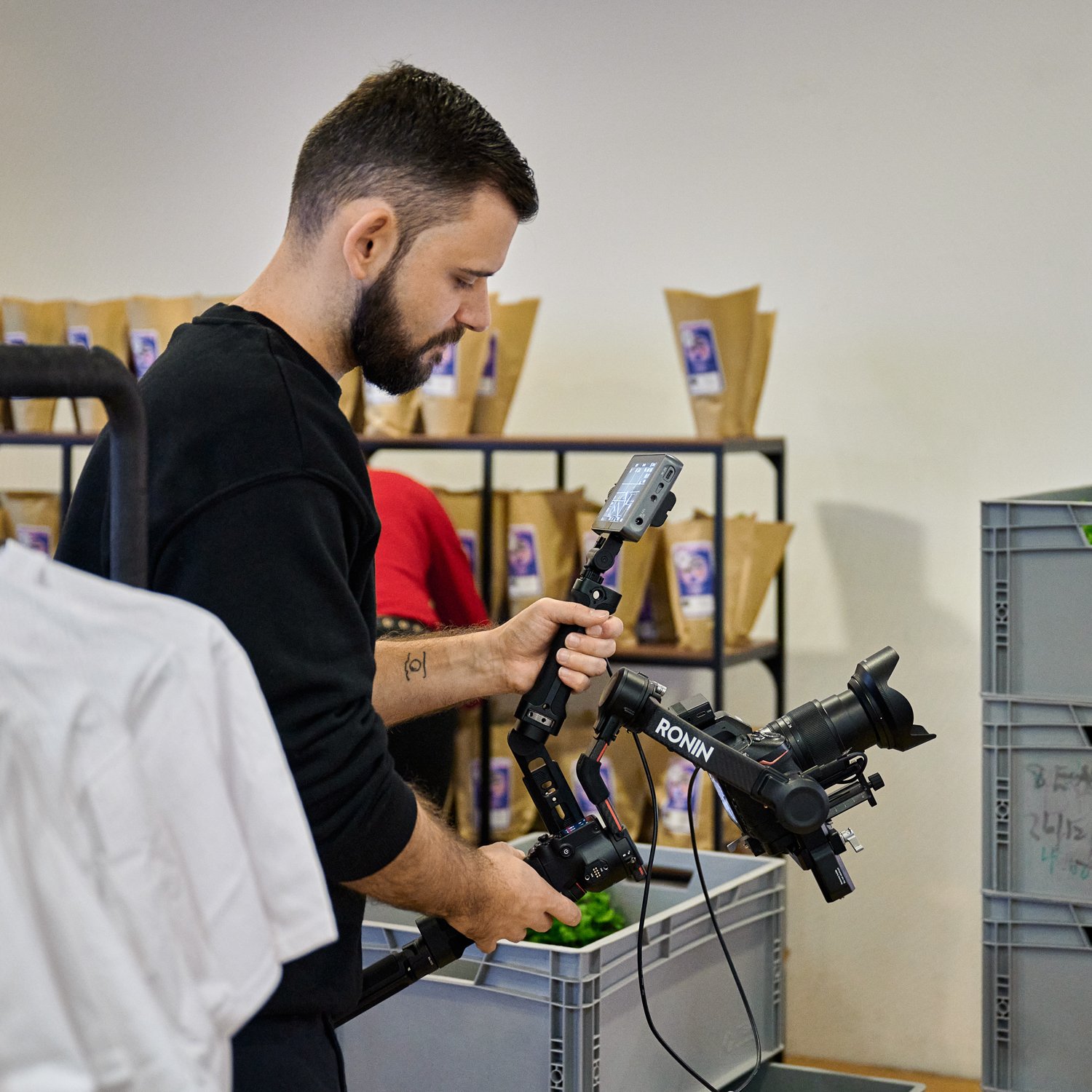 Ein Mann filmt mit einer professionellen Kamera in einem Lagerraum.