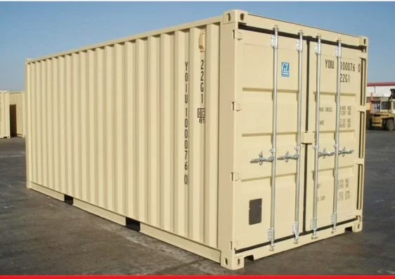 A beige shipping container placed on a paved surface with a clear blue sky in the background.