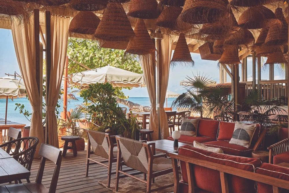 Three women singing into a microphone at night with colorful bokeh lights in the background, enjoying a lively moment together.