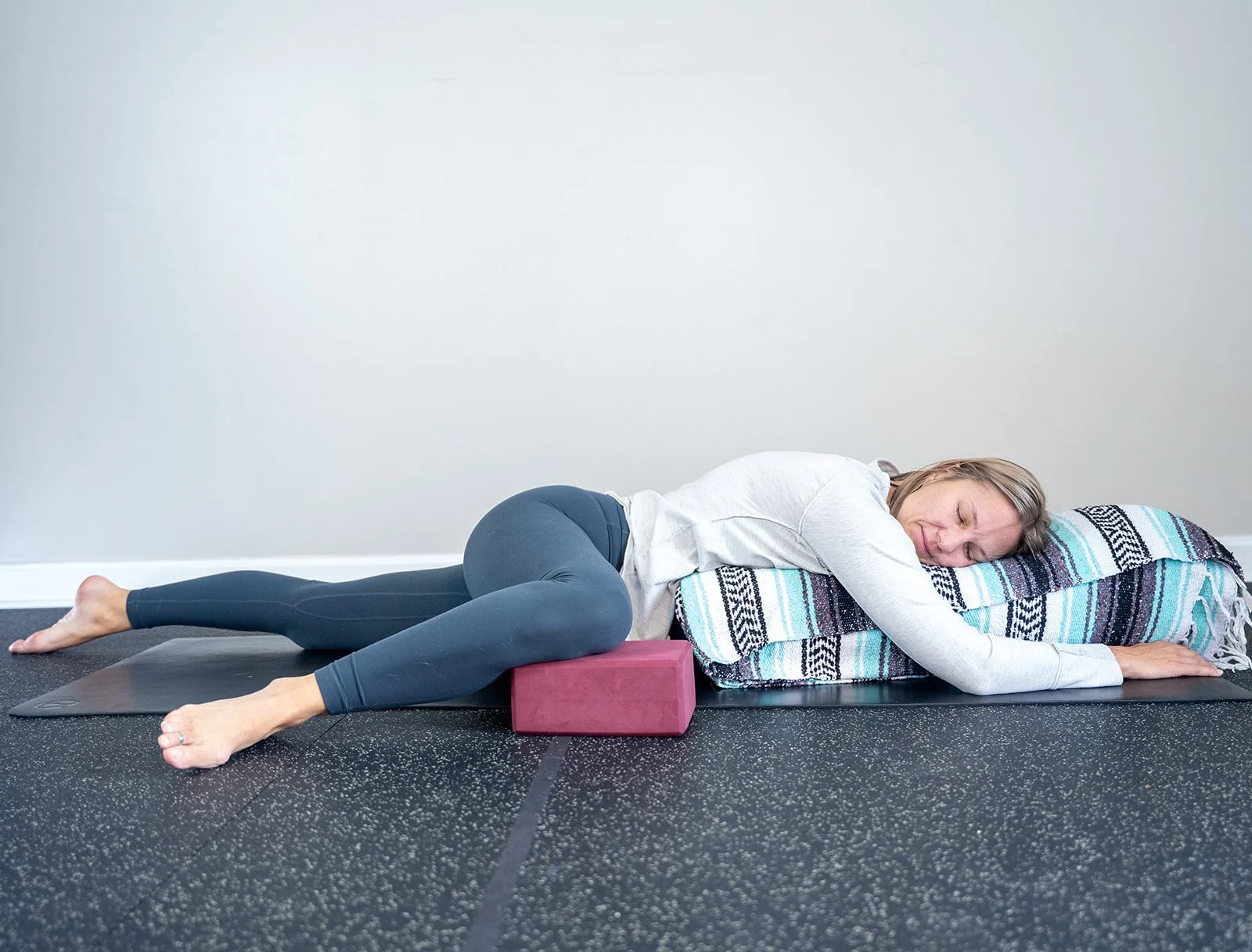 a person resting on a yoga bolster and blanket