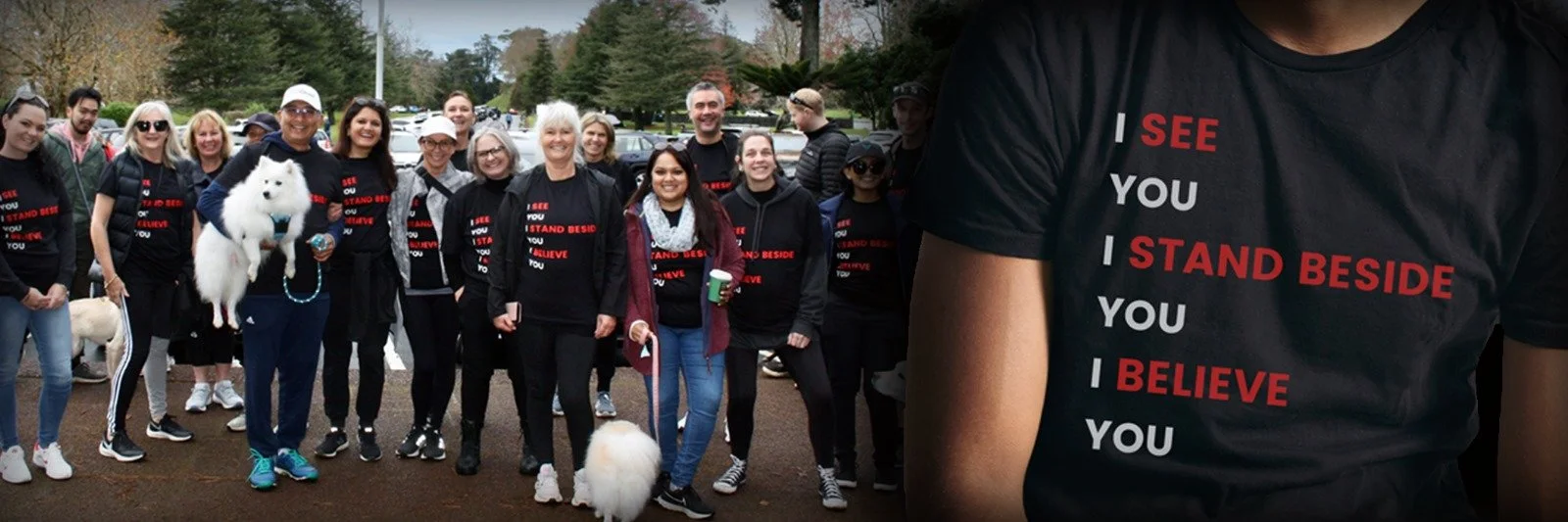 Group of people outdoors wearing matching black t-shirts with red and white text that reads 'I SEE YOU, I STAND BESIDE YOU, I BELIEVE YOU'.