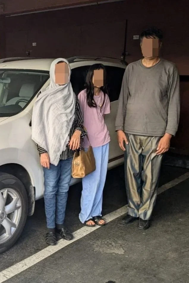 A mother, father, and teenage daughter stand in front of a white SUV