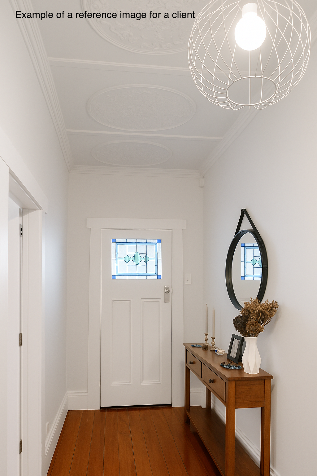 Entryway with white door, stained glass window, wooden console table with decorations, and oval mirror on white wall.