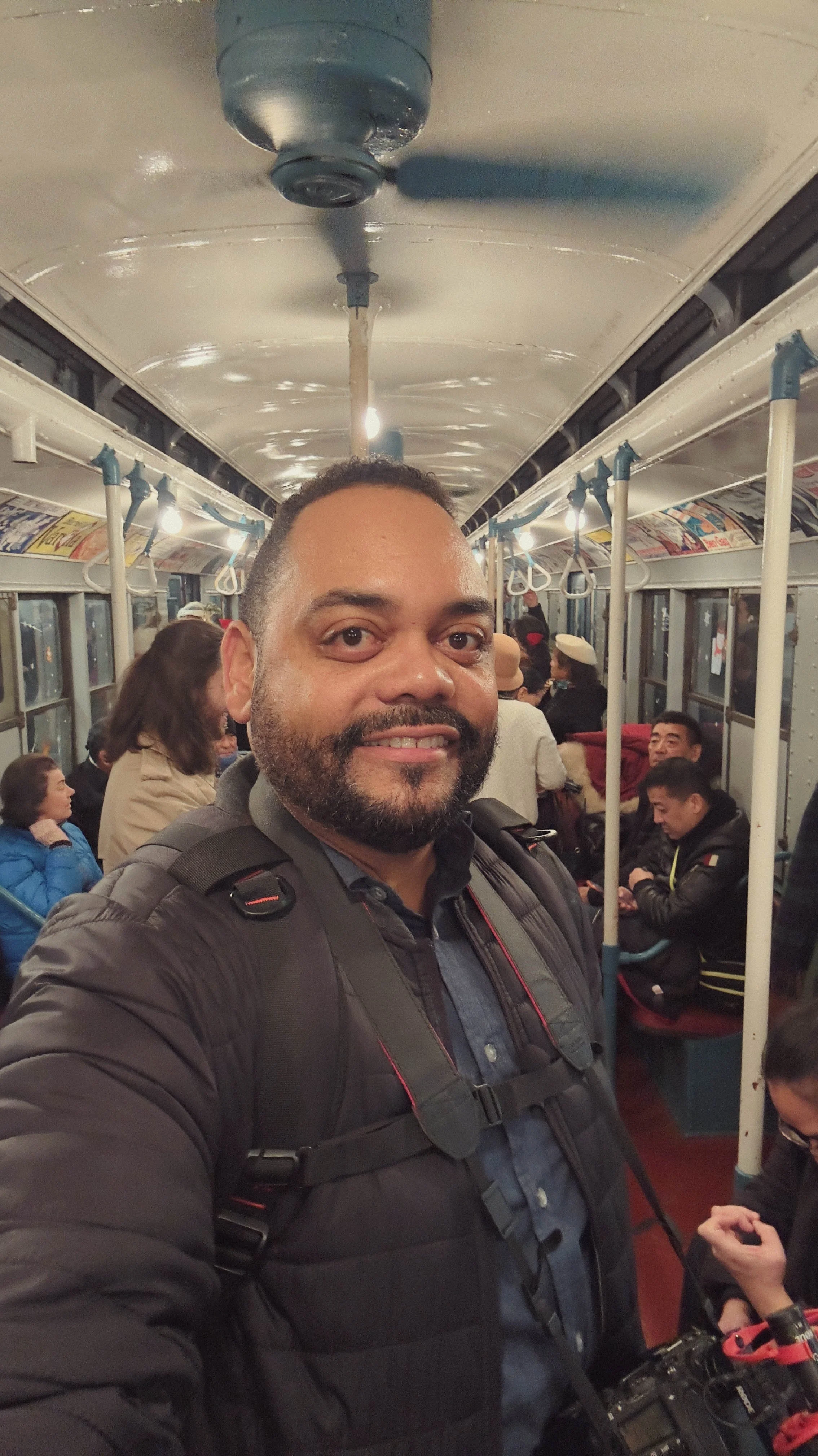 crowded subway train, with passengers seated and standing around.