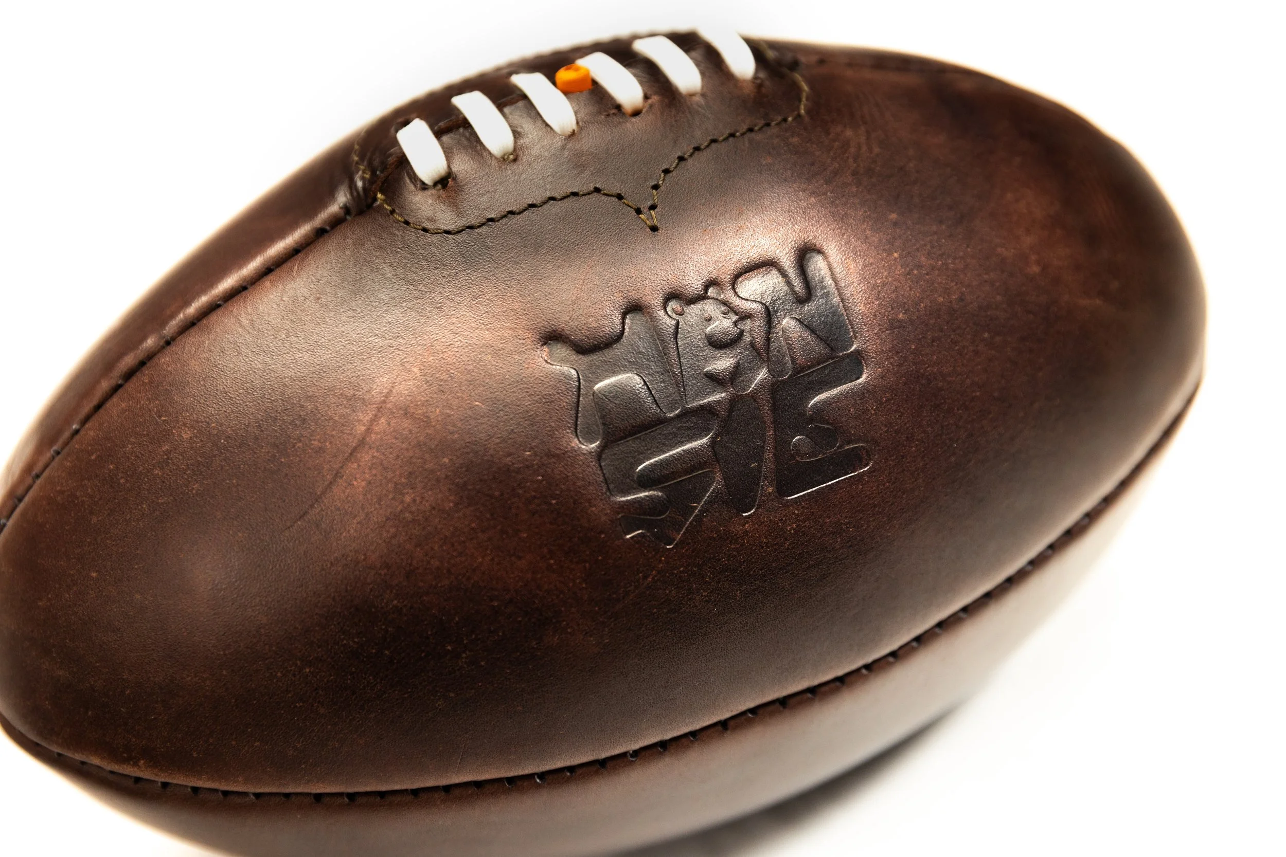 Close-up of a vintage leather football with embossed brand logo and white laces.