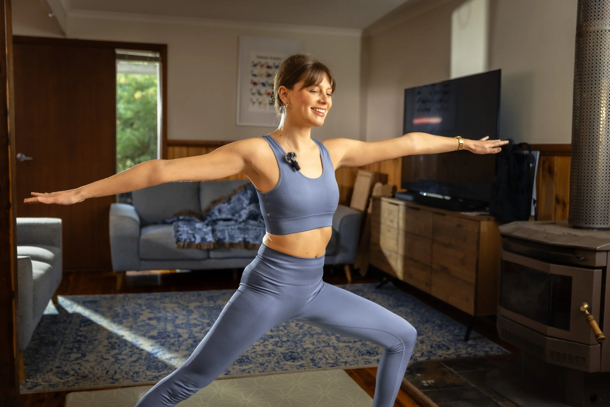 Woman in activewear practicing yoga in a living room.