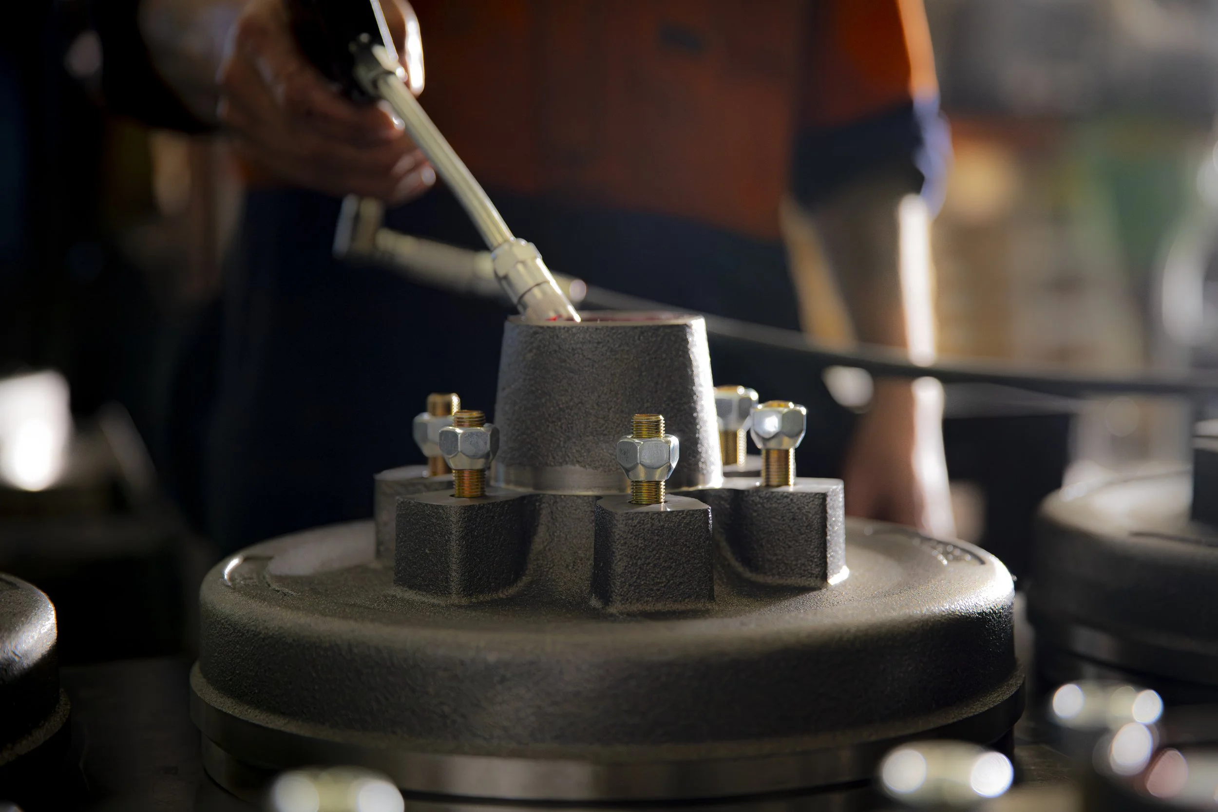 A person inspecting a mechanical component with a robotic arm in a workshop or manufacturing setting.