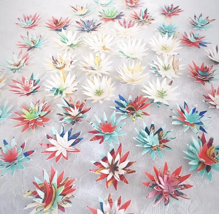 Multi-Coloured Paper Flowers scattered on a white cloth.
