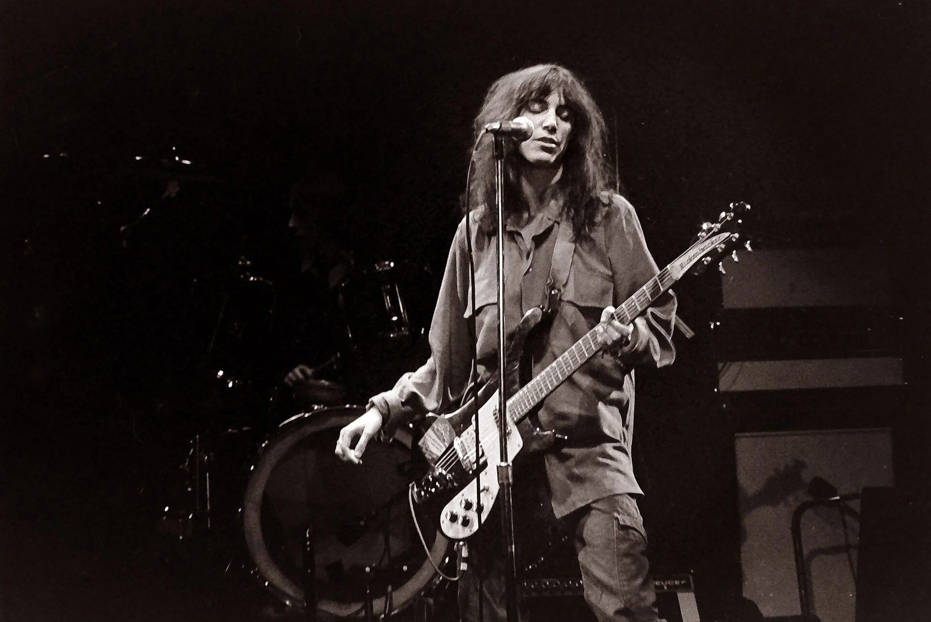 Patti Smith black and white photo of performing on stage with a guitar.