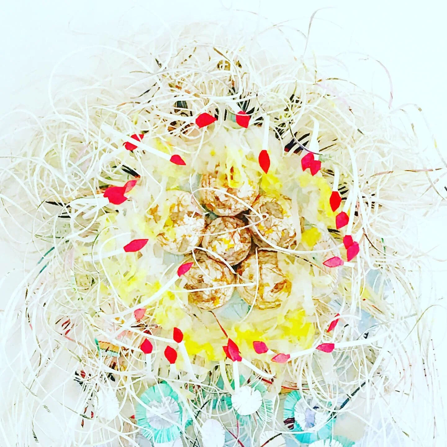 A paper sculpture featuring white and yellow upcycled paper, red accents, and intricate white and blue round paper layers to replicate a Jellyfish.