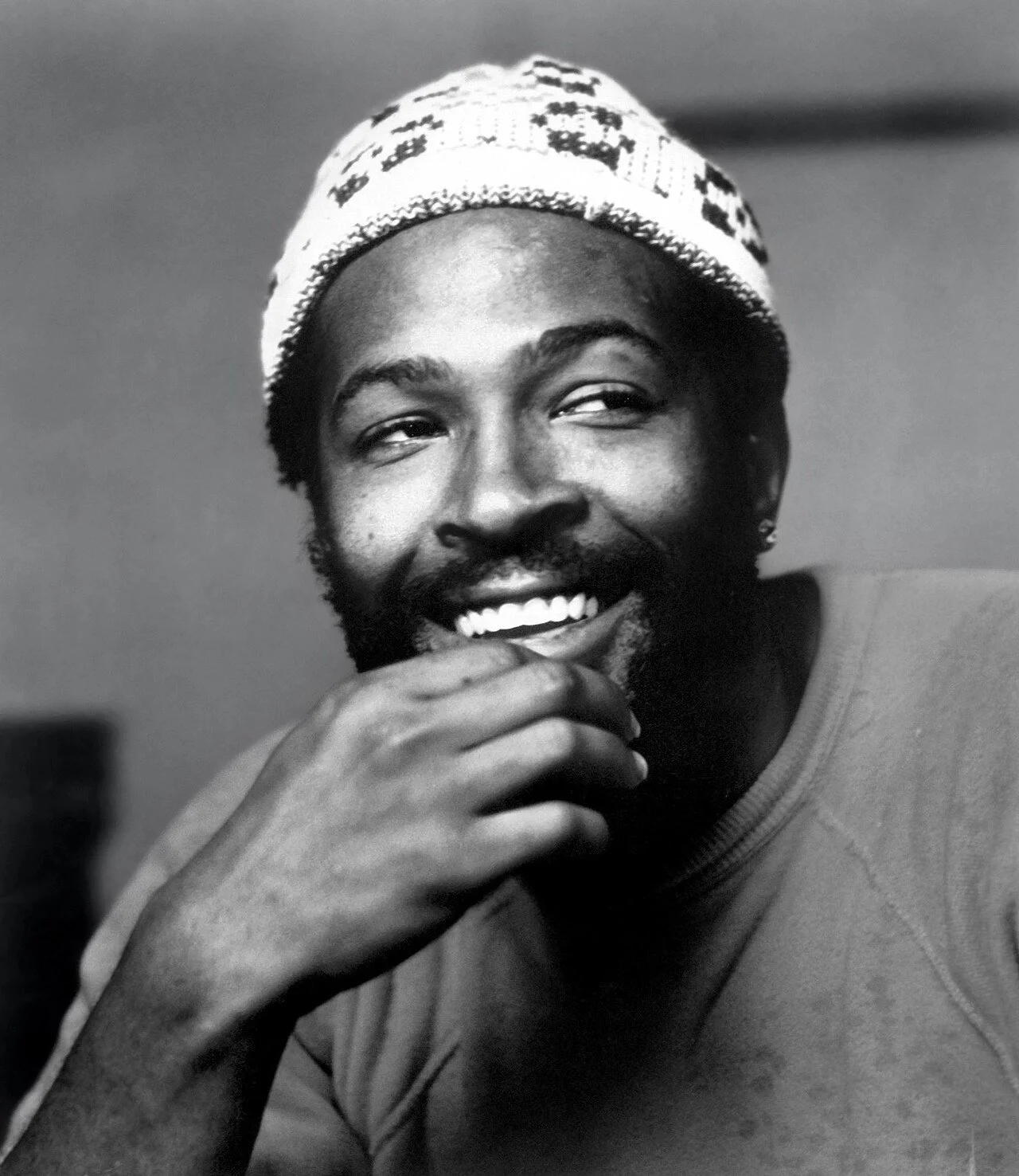Marvin Gaye portrait in B+W with beanie and T-shirt smiling.