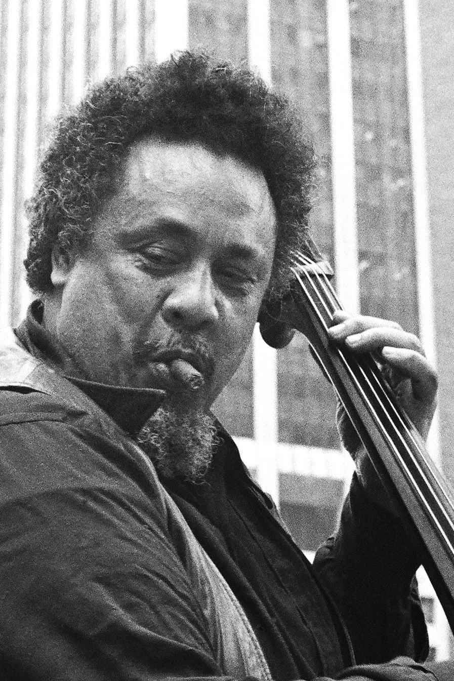 Charles Mingus playing double base and smoking a cigar.