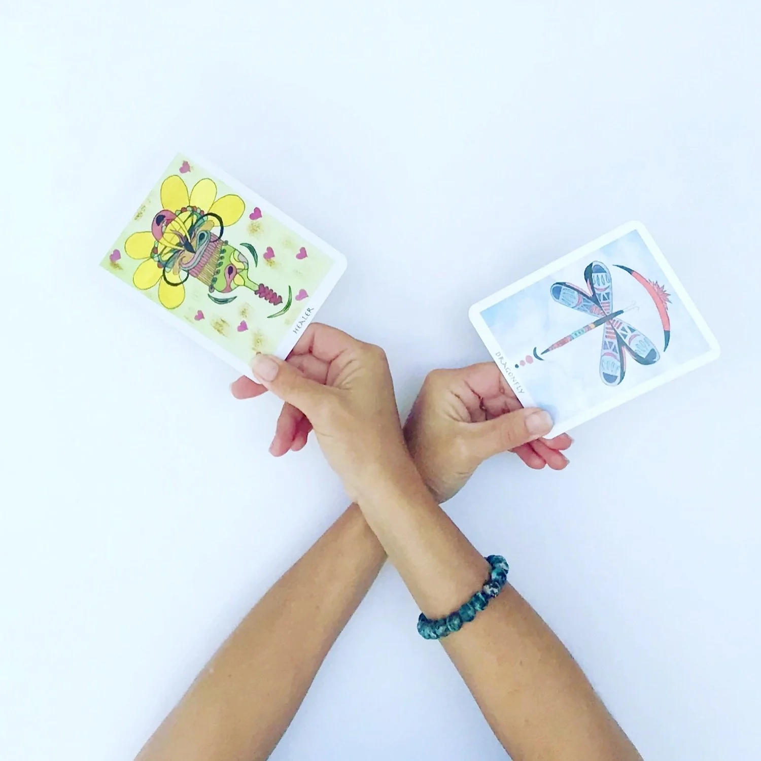 Two hands holding illustrated playing cards on a white background.