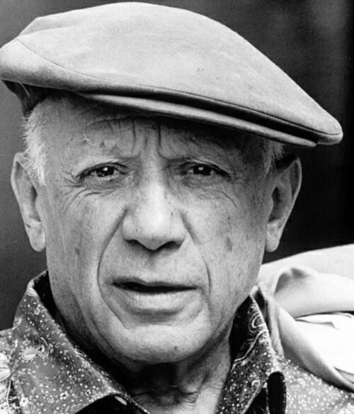 Pablo Picasso portrait in black and white wearing a flat cap and collared shirt.