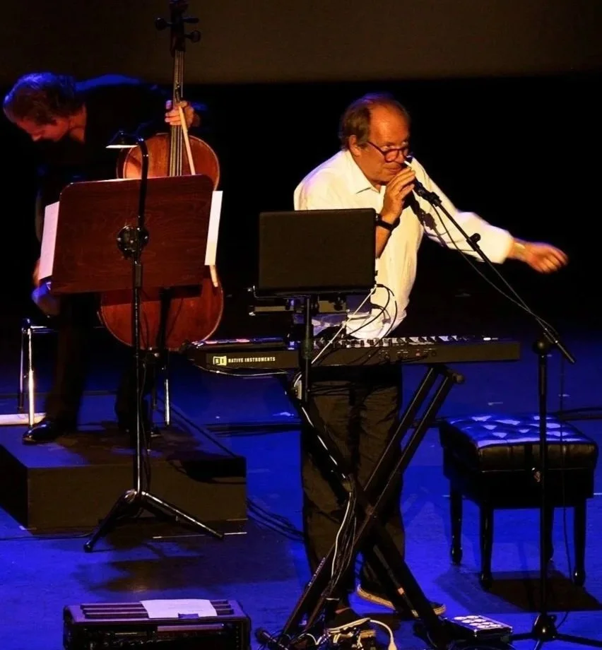 Hans Zimmer on on stage with Cello musician and speaking into microphone.
