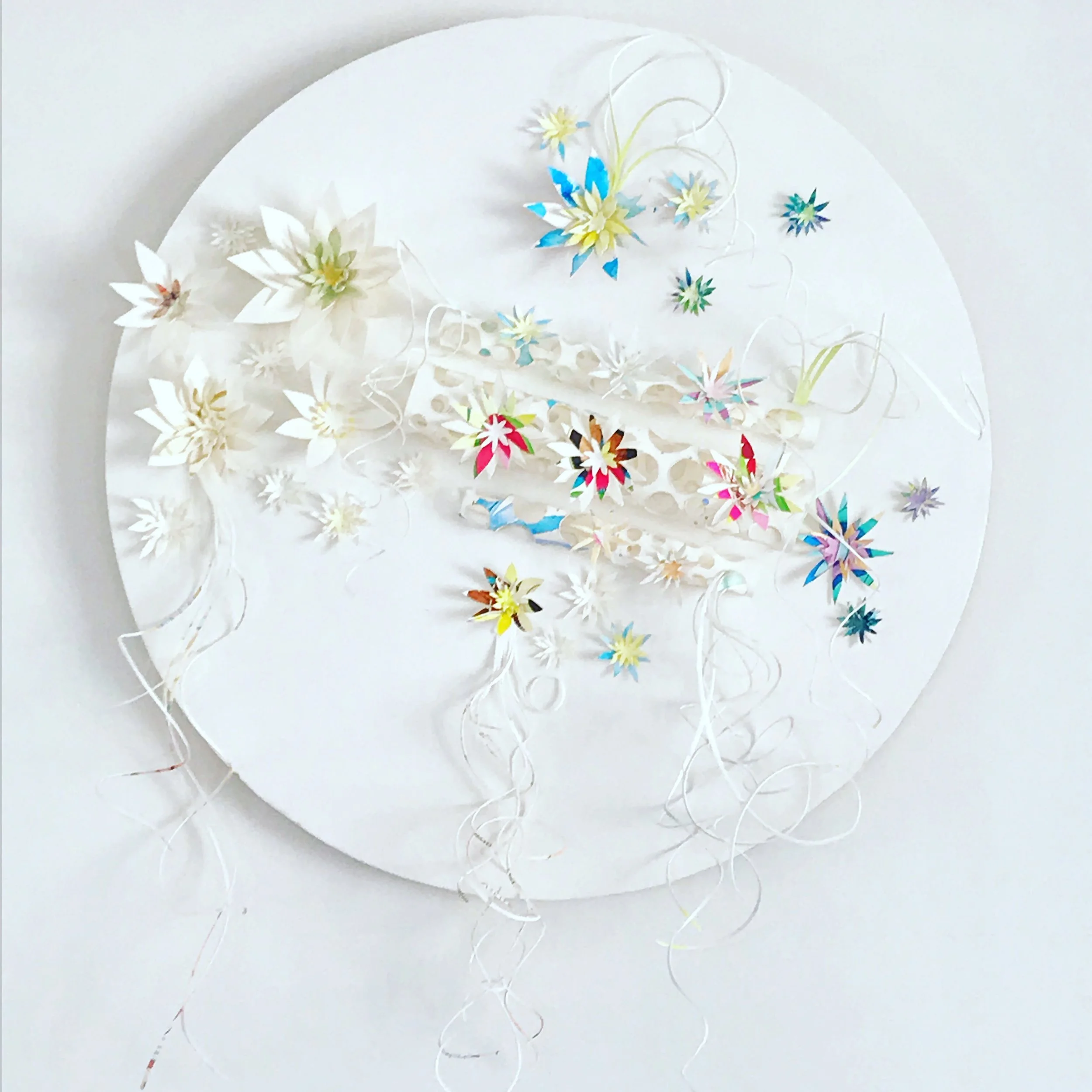 Paper Sculpture by artist Leesa Maree featuring paper flowers and curly strands on a round mandala wall hanging.