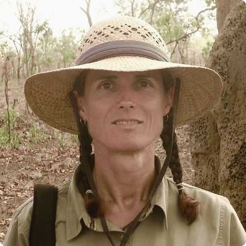 Ricki stands in the field with a wide brimmed hat on looking at the camera
