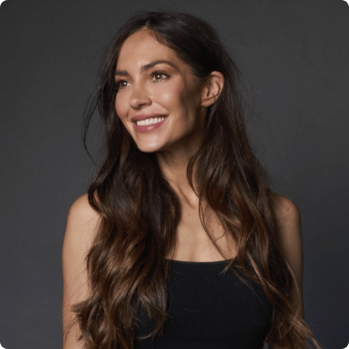 Natalie has long brown hair. She is looking away from the camera and smiling.