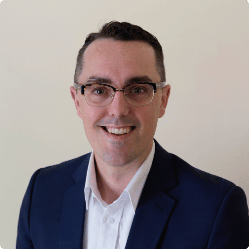 Dr Luke Smith is wearing glasses, a shirt and suit jacket.