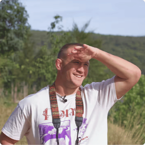 Mitch is standing in the sunshine, binoculars around his neck, hand up to his face to shield from the sun