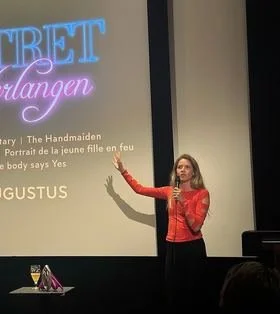 Anna Marah Jansen als spreker op het podium, sprekend met een microfoon